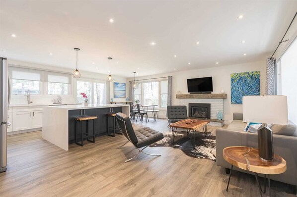A spacious living area with a kitchen, a fireplace, and a television.