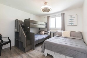 Een slaapkamer met een stapelbed, een enkel bed, een kleine tafel en een stoel.