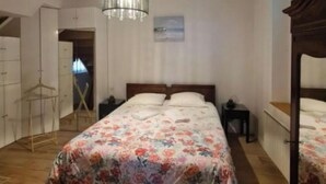 Un dormitorio con una cama, una lámpara colgante, un aparador de madera y una ventana.
