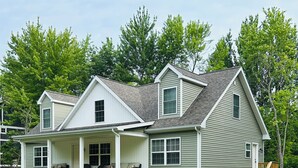 A two-story house with a covered porch and a gravel driveway.