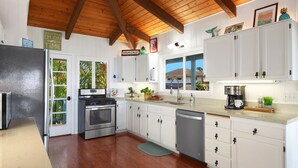 Une cuisine moderne avec des armoires blanches, des appareils en acier inoxydable et des poutres en bois au plafond.