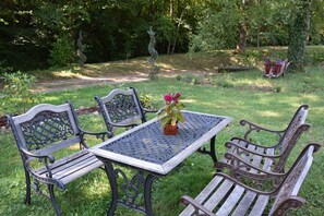 Ein Garten mit einem Metalltisch und vier Bänken.