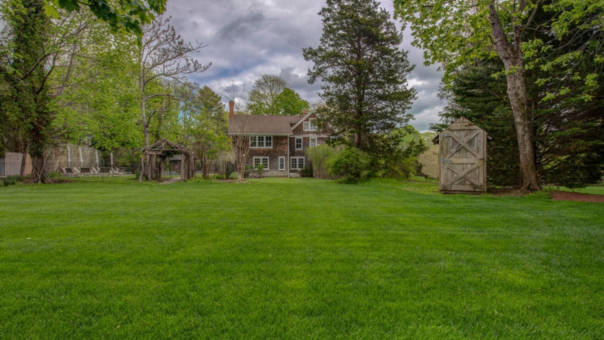 A large, two-story house with a well-maintained lawn and a wooden barn.