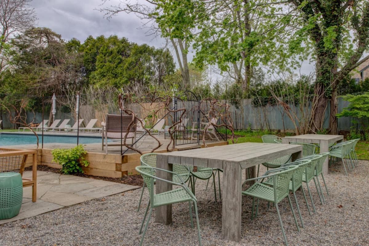 Um pátio externo com piscina, rodeado por árvores e um deck de madeira.