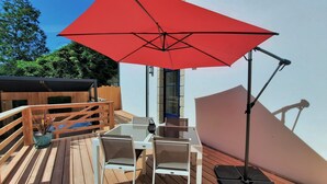 A wooden deck with outdoor furniture, a red umbrella, and a stepper. - At the water's'edge "Nymphea (Saint-Barthelemy)