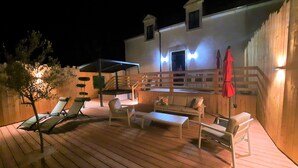An outdoor deck with wooden flooring, a covered seating area, and a staircase leading to an upper level. - At the water's'edge "Nymphea (Saint-Barthelemy)