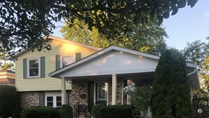 A two-story house with a front porch, a well-maintained lawn, and a pathway leading to the entrance.