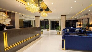 Un moderno vestíbulo de hotel con mostrador de recepción, zona de estar e iluminación decorativa.