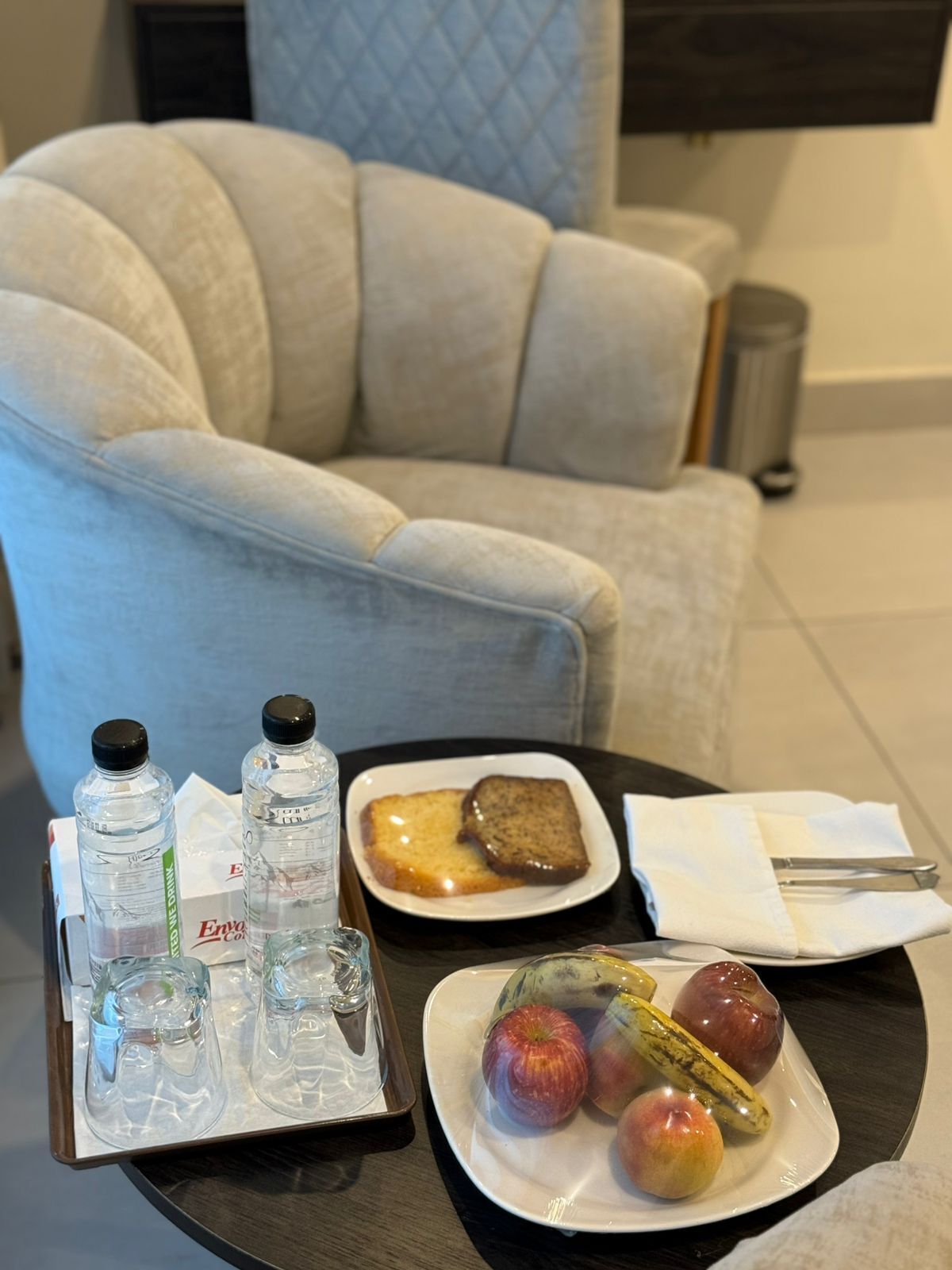 A tray with water bottles, toast, and fruit on a table in a hotel room.
