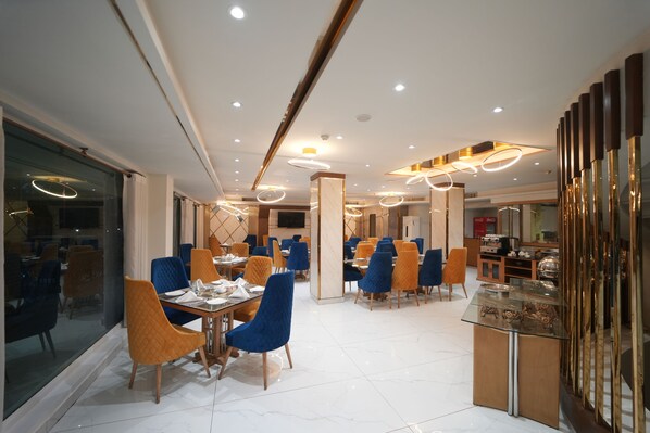 A modern dining area with multiple tables and chairs, a glass display case, and recessed ceiling lighting. - Envoy Continental Hotel, Blue Area, Islamabad (Islamabad)