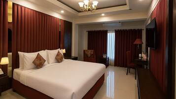 Quarto de hotel com uma cama grande, televisão, escrivaninha e uma cadeira.