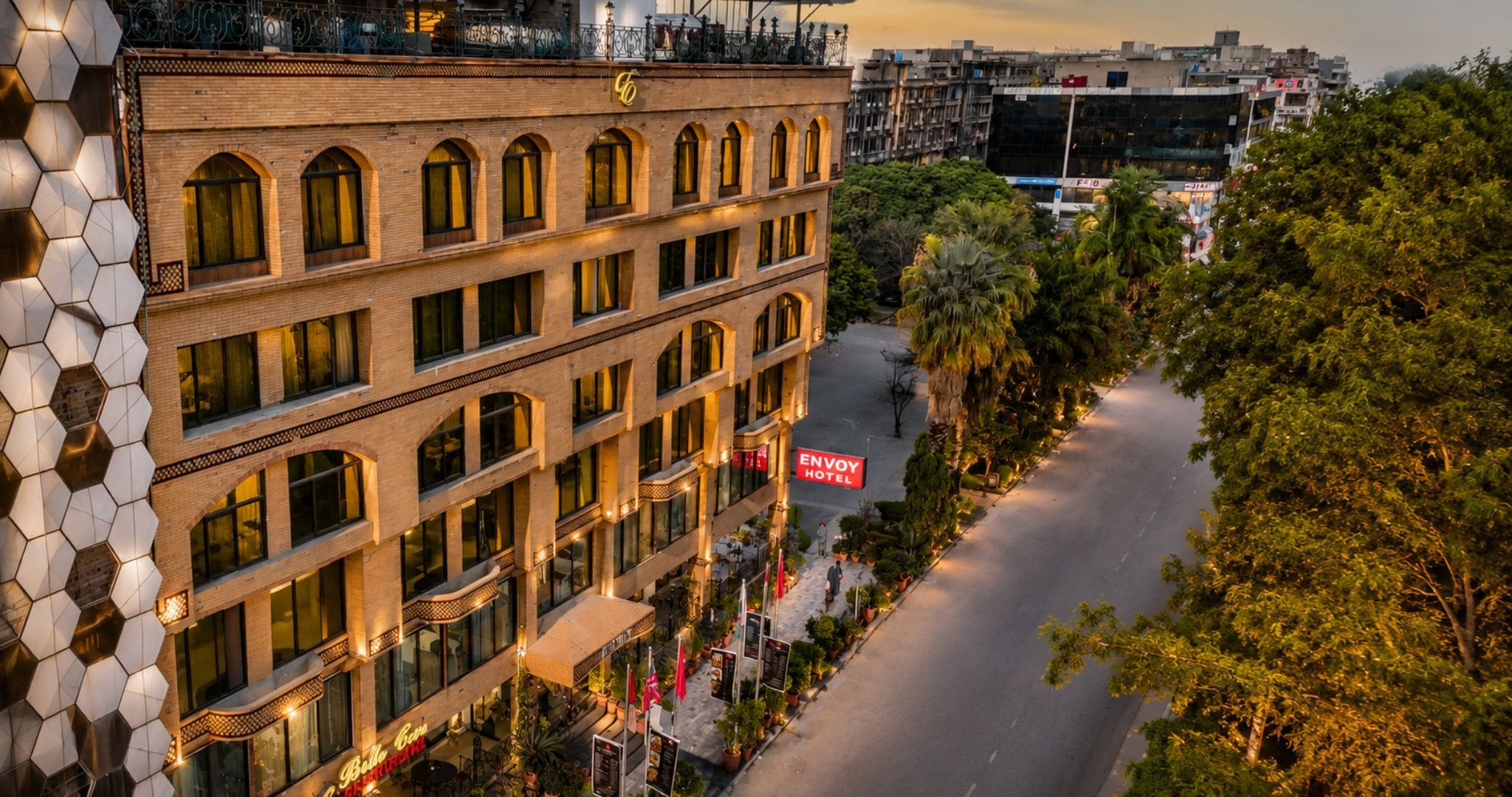 A hotel with multiple floors, a prominent sign for the Envy Hotel, and a street view with trees and other buildings.