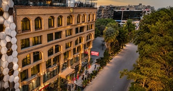 Un hotel de varios pisos, con un letrero visible del Hotel Envy, y vista a la calle con árboles y otros edificios.