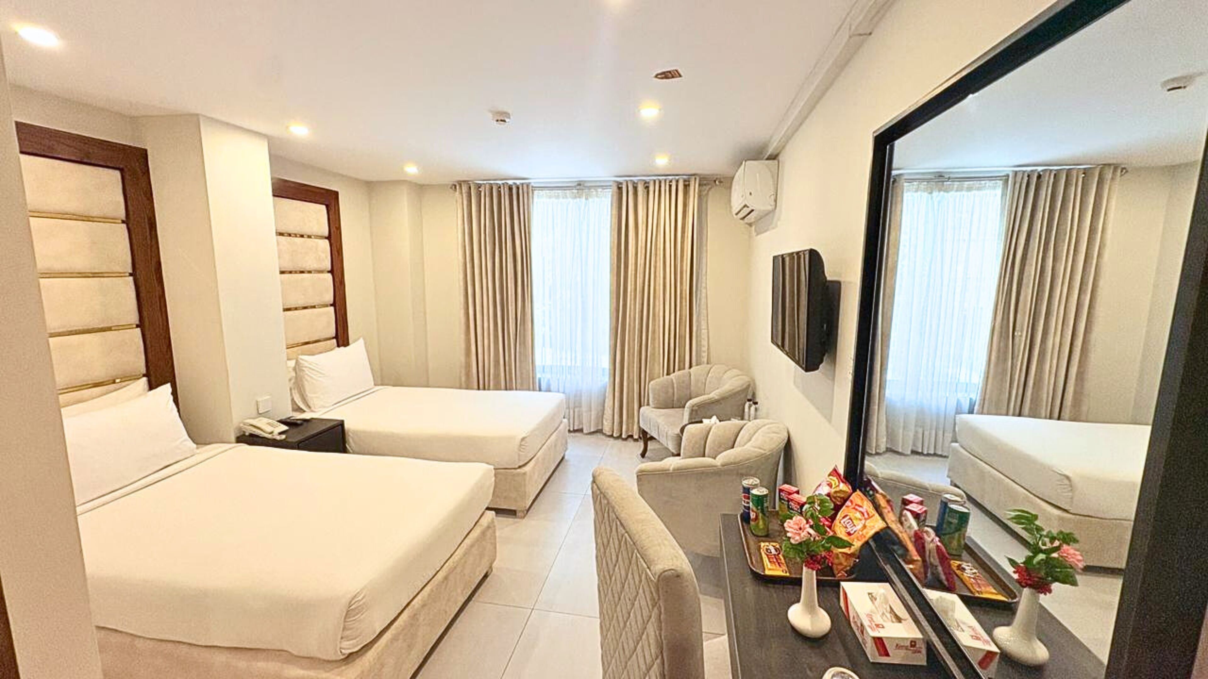 Habitación de hotel con dos camas, un sofá, un televisor y un minibar.