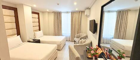 Habitación de hotel con dos camas, un sofá, un televisor y un minibar.