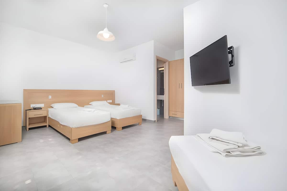Una habitación de hotel moderna con una cama grande, un televisor montado en la pared y un escritorio pequeño.