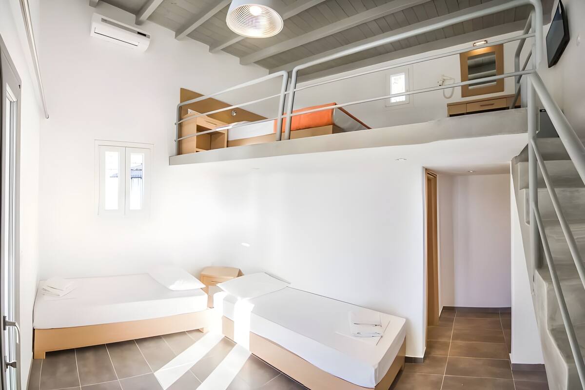 Una habitación moderna, de varios niveles, con un altillo, una escalera y una cama.