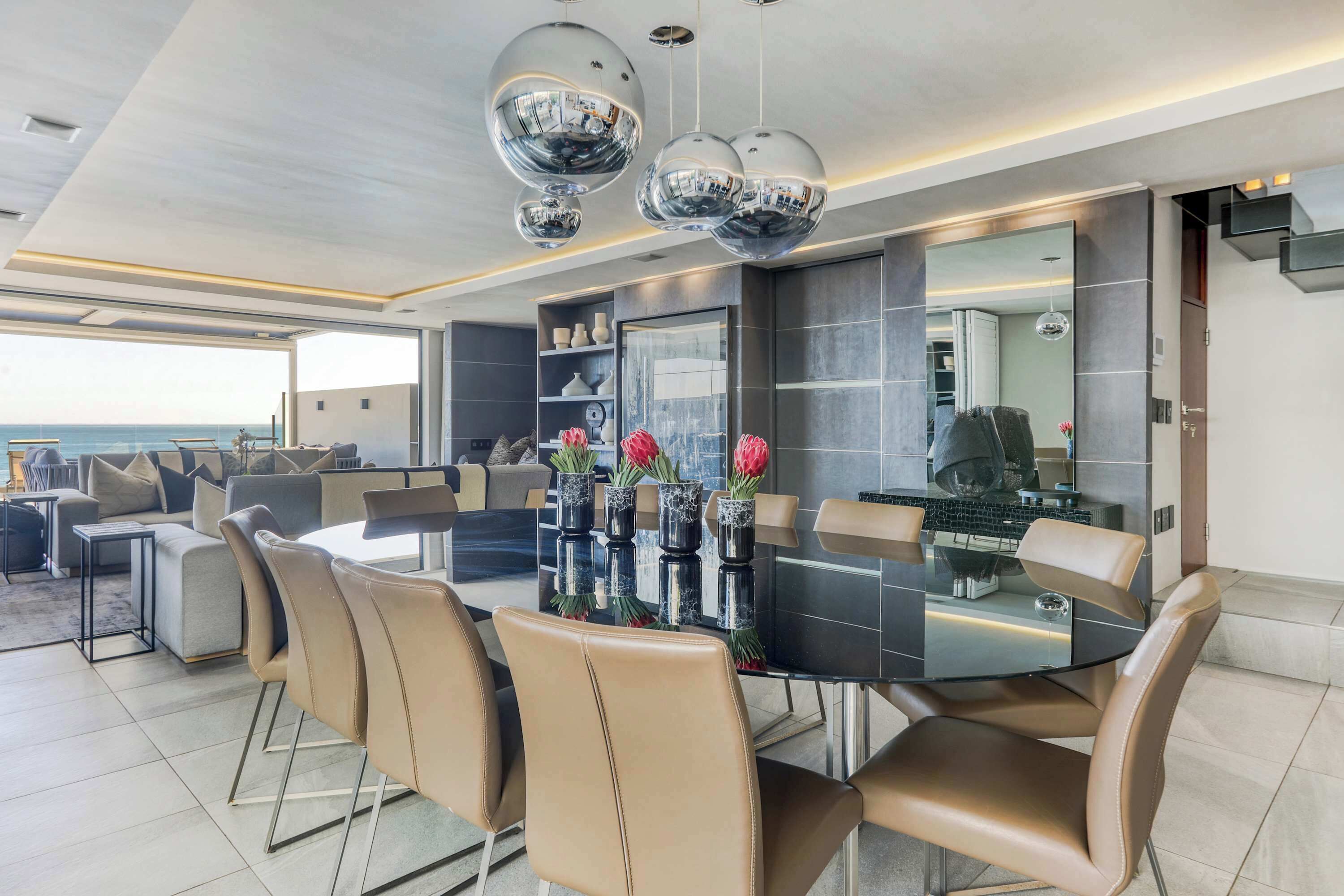 Un espace repas moderne avec une table ronde, des chaises en cuir et des vases décoratifs.