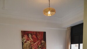 Ein Schlafzimmer mit einem großen Bett, einem Kopfteil mit einem Gemälde, einem kleinen Tisch und einem Stuhl.