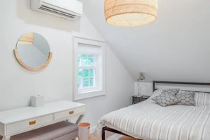 Ein Schlafzimmer mit Bett, Nachttisch und Fenster.