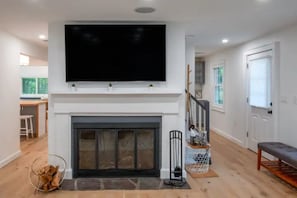 Ein Wohnzimmer mit Kamin, einem Wand-Fernseher und einer Bank.