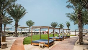 A beachside resort with sun loungers, wooden deck, and palm trees.
