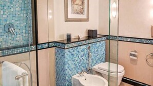 A bathroom with a glass shower enclosure, a tiled sink area, and a toilet.