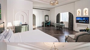 A hotel room with a large bed, a desk, a chair, a television, and a fireplace.