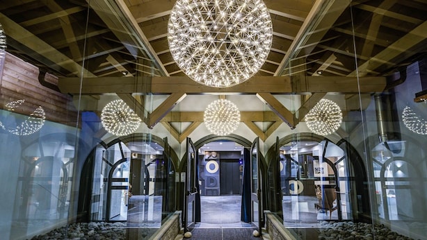 A modern interior with a central glass corridor, wooden beams, and spherical light fixtures.