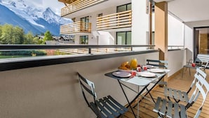 A balcony with a table set for breakfast, overlooking a mountain landscape.