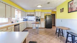 A kitchen with white cabinets, a stainless steel refrigerator, and a yellow wall. - Charming East Dallas Home (Dallas)