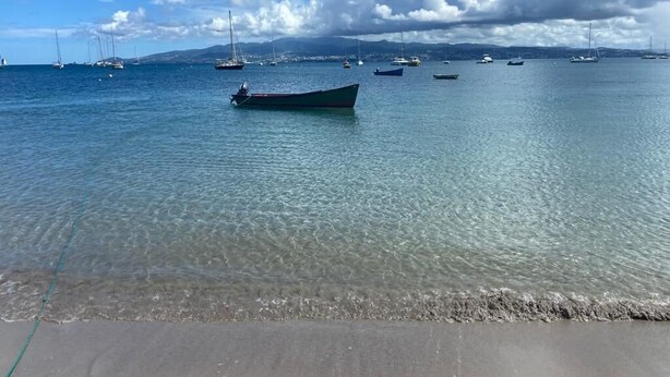 Una playa con agua cristalina y barcos.