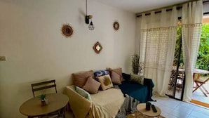 Una sala de estar con sofá, mesa de centro, mesa de comedor con sillas y una alfombra estampada.