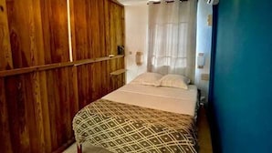 Un dormitorio con cama, armario de madera, pared azul y ventana con cortinas.