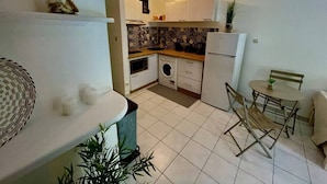 Una cocina compacta con lavadora, refrigerador y comedor con mesa y sillas.