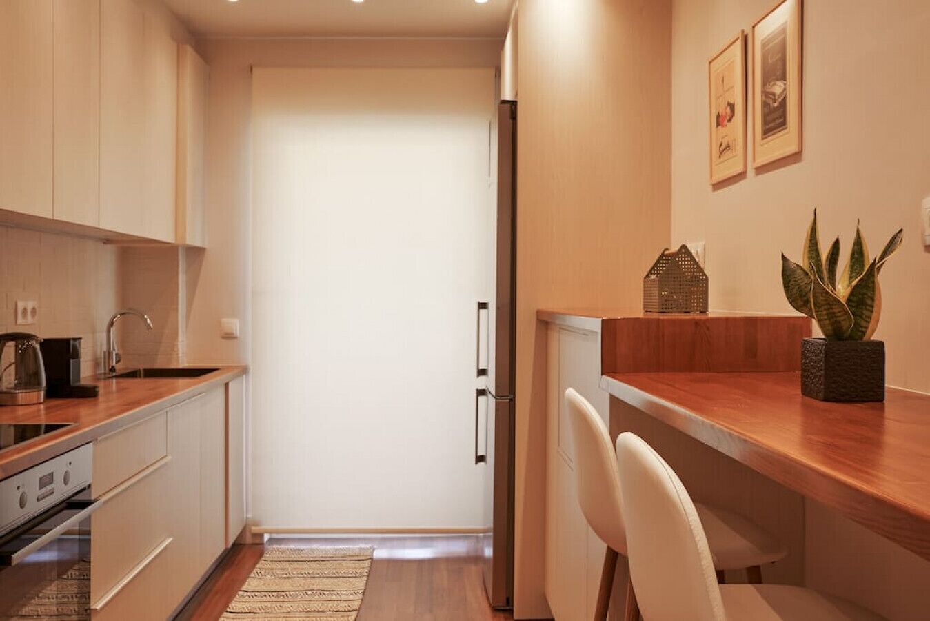 A compact kitchen with a refrigerator, a coffee maker, and a plant on the counter.