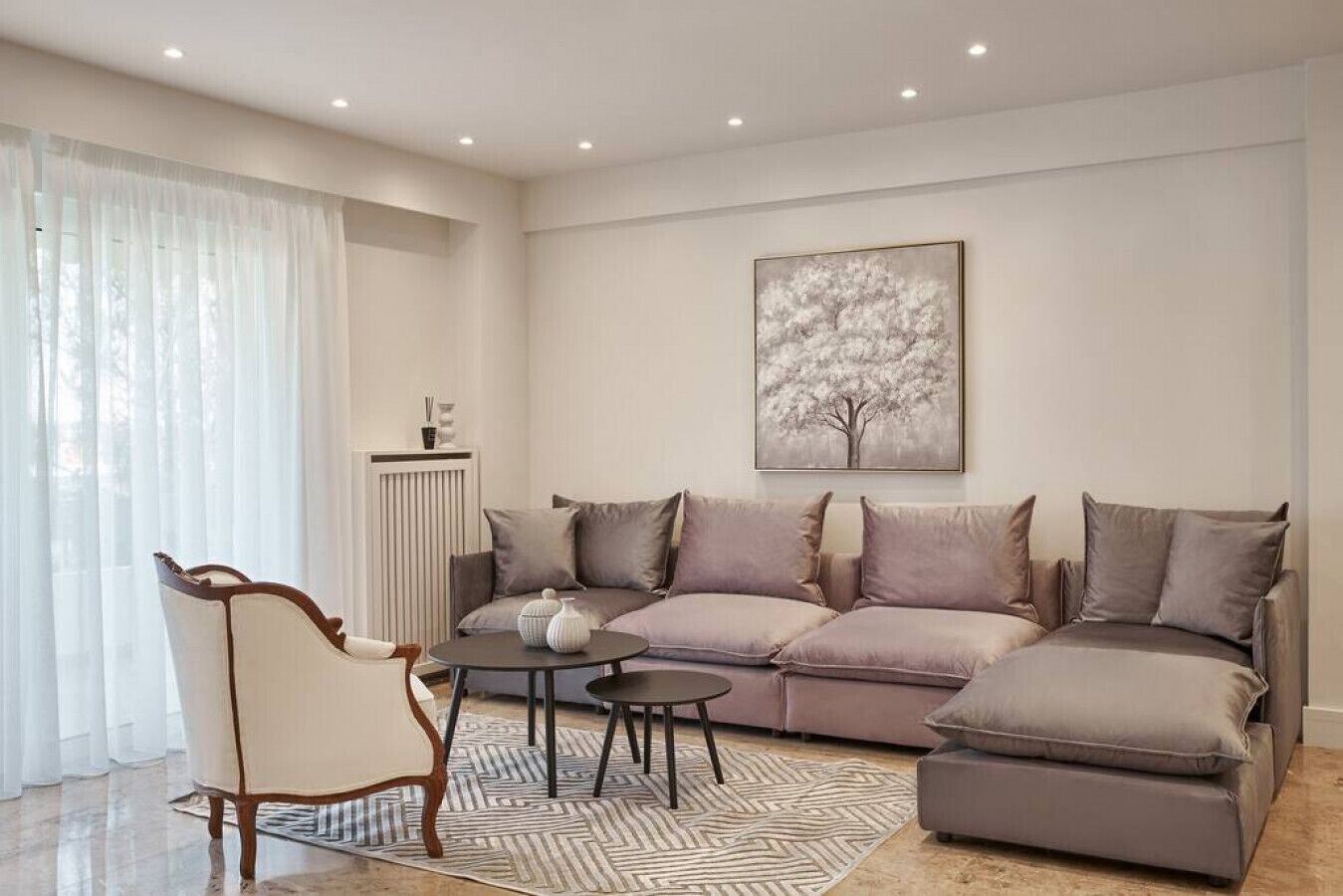 A modern living room with a sofa, a chair, a small table, and a radiator.