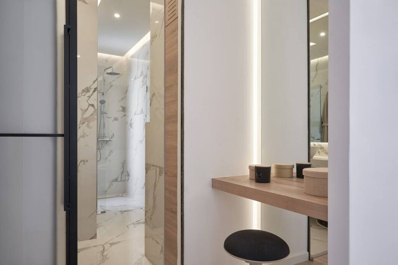 A modern bathroom with a marble shower, a wooden vanity, and a mirror.