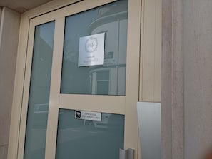 A door with a glass panel and two signs: one indicating surveillance and another with a year and name.