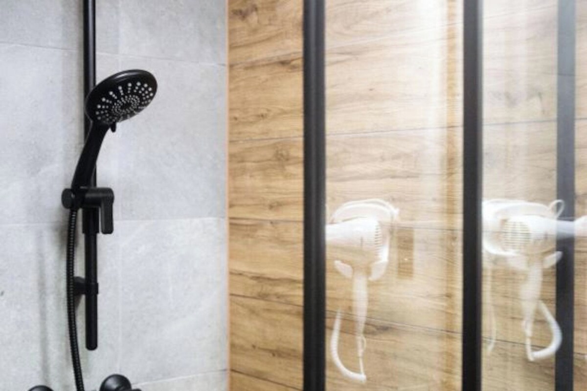 A shower with a handheld head, a handheld body, and a wall-mounted showerhead.