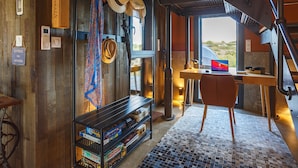 A room with a desk, chair, and a shelf with board games.