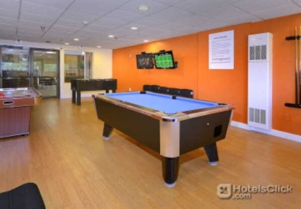 Enjoy a game of pool in this room with a pool table, glass door leading to an outdoor area, and a convenient cabinet for storage.