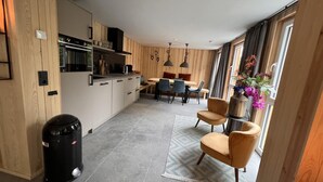 Moderni keittiö, jossa on puupanelointi, ruokailutila sinisillä tuoleilla ja suuri ikkuna, jossa on verhot.