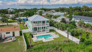 A two-story house with a pool and a fenced backyard. - Surf-N-Santa, 6 BR/4 BA, Private Pool with Hot Tub, West End PCB, Sleeps 18 (Panama City Beach)