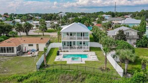 A two-story house with a pool, surrounded by a fence and palm trees. - Surf-N-Santa, 6 BR/4 BA, Private Pool with Hot Tub, West End PCB, Sleeps 18 (Panama City Beach)