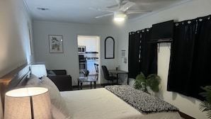 A hotel room with a bed, a desk, a chair, a lamp, and a ceiling fan. - Bella Is A Happy Place. (Lehigh Acres)