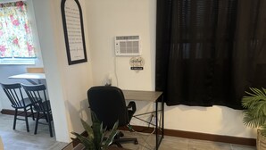 A room with a glass-top table, a black office chair, a potted plant, a wooden desk, and a black curtain. - Bella Is A Happy Place. (Lehigh Acres)