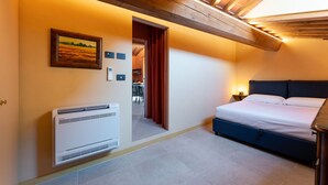 Une chambre à coucher avec un lit, un radiateur, un tableau et une porte donnant sur une autre pièce.