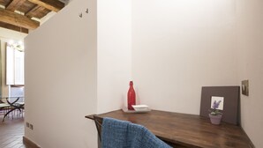 A room with a wooden table, a red bottle, a white bowl, a blue towel, and a potted plant.