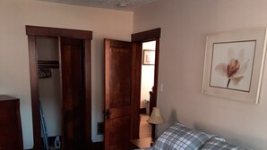 Een slaapkamer met een bed, een deur, een lamp en een lijst met een afbeelding aan de muur.